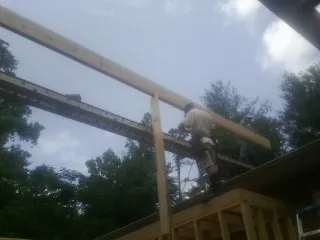 Carpenter setting a ridge beam over a new addition frame — Ice Dam Removal by Roofing Brothers in Owasso