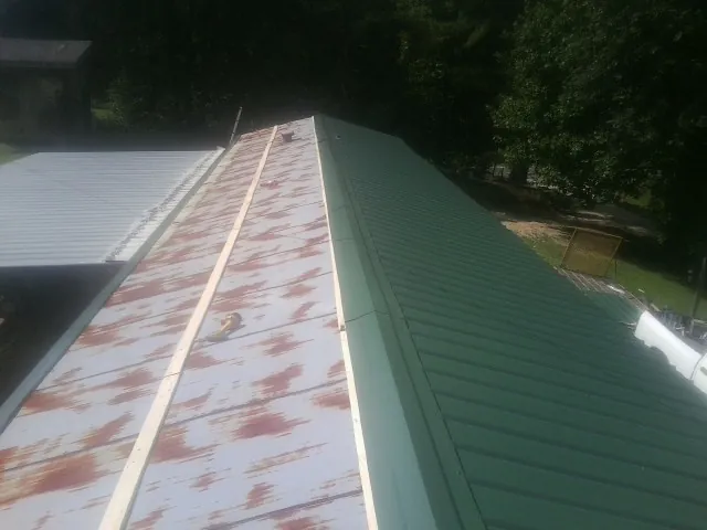 Old rusted panels beside newly installed green metal roofing — Wind Damage Roof Repair by Roofing Brothers in Owasso