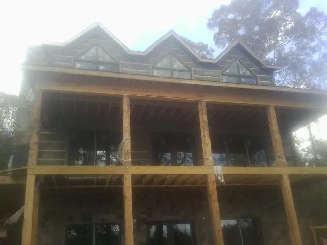 Dormers and porch framing on a large log home under construction — Roof Coating work by our crew in Owasso