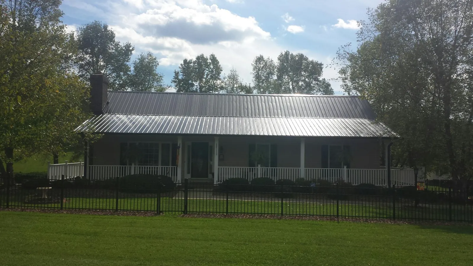 Gray metal roof on a brick ranch with a full width front porch — Gutter Guard Installation work by our crew in Owasso