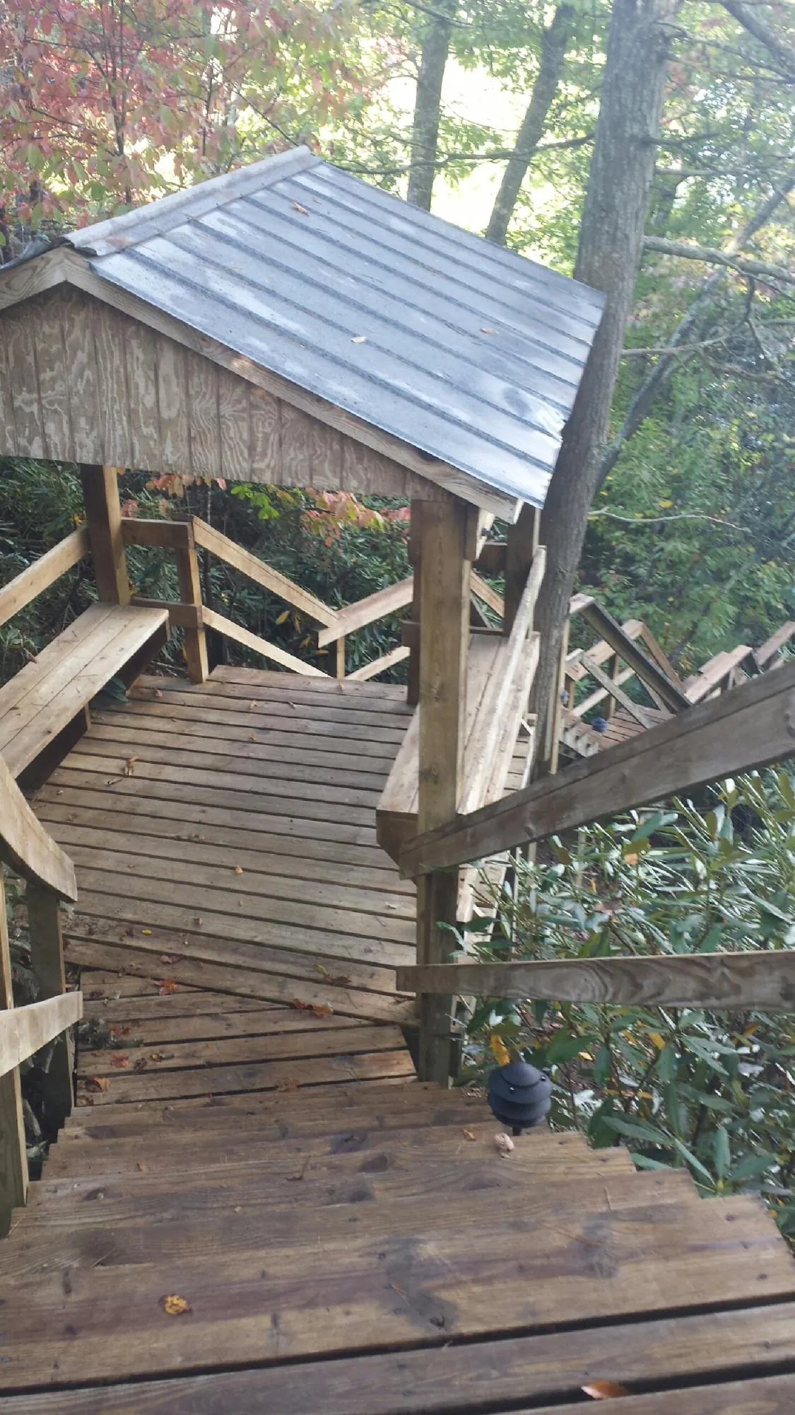 Metal roofed shelter over wooden steps on a wooded walkway — Skylight Repair & Installation work by our crew in Owasso