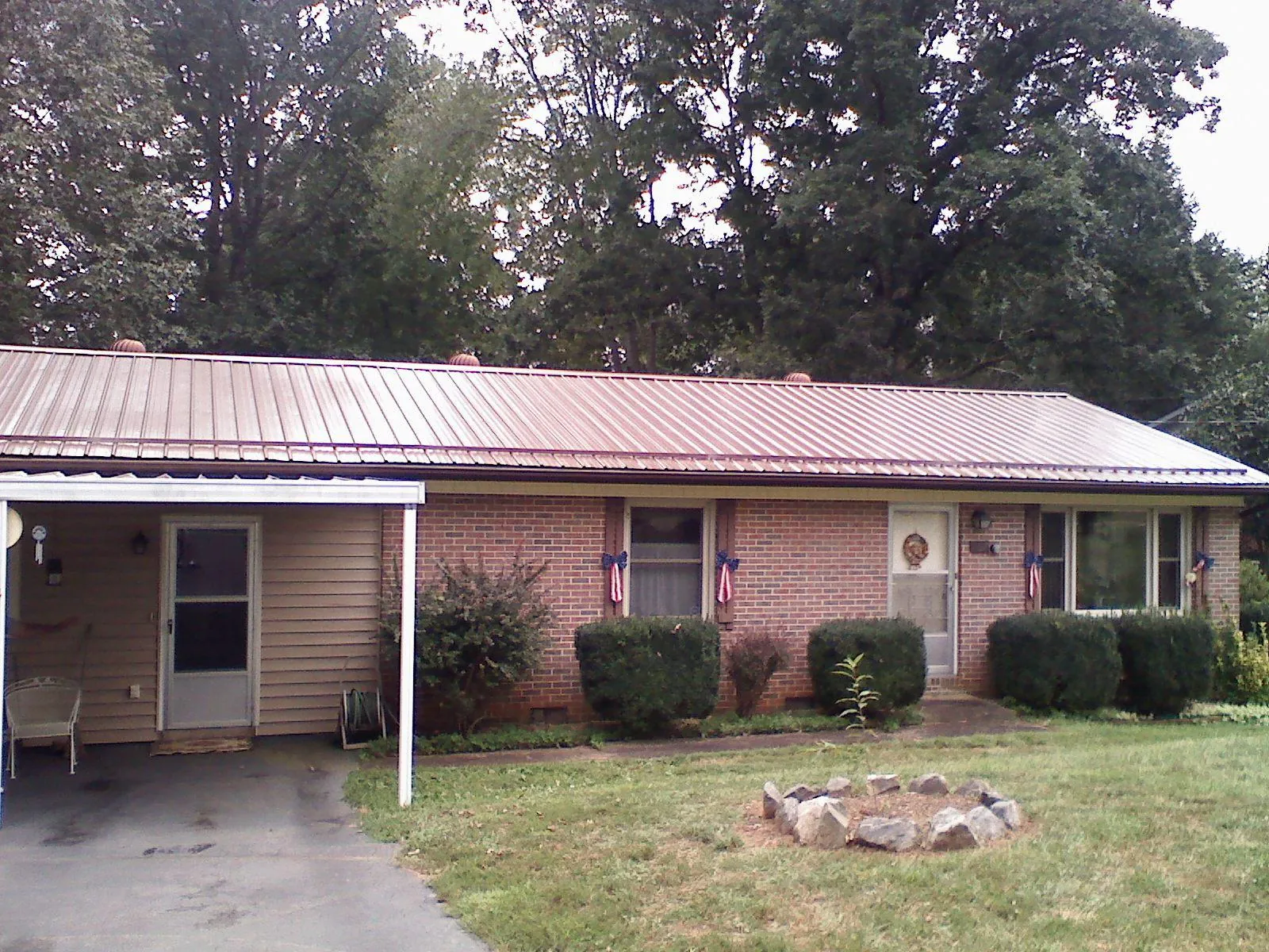 Bronze metal roof and carport on a brick ranch home — Roof Repair work by our crew in Owasso