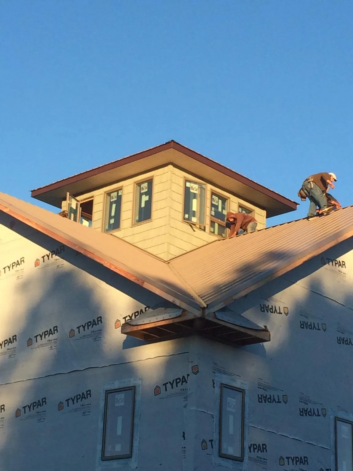 Roofers working around a rooftop cupola on a new metal roof at sunset — Roof Waterproofing in Owasso by Roofing Brothers
